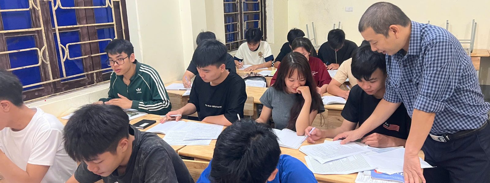 Giáo viên kèm cặp học viên trong giờ ôn tập buổi tối, chuẩn bị cho kỳ thi tốt nghiệp THPT
